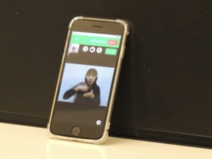 スマホの写真。電話リレーサービスの利用者画面が映っていて、通訳オペレータが手話通訳をしている画面が映っている。